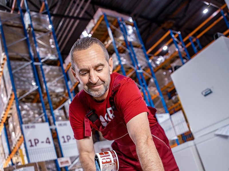 A BIOCARD warehouse employee sealing a SafePack container with branded tape