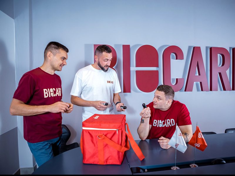 BIOCARD team members in branded T-shirts with sensors and a red SafePack thermal bag at a meeting table